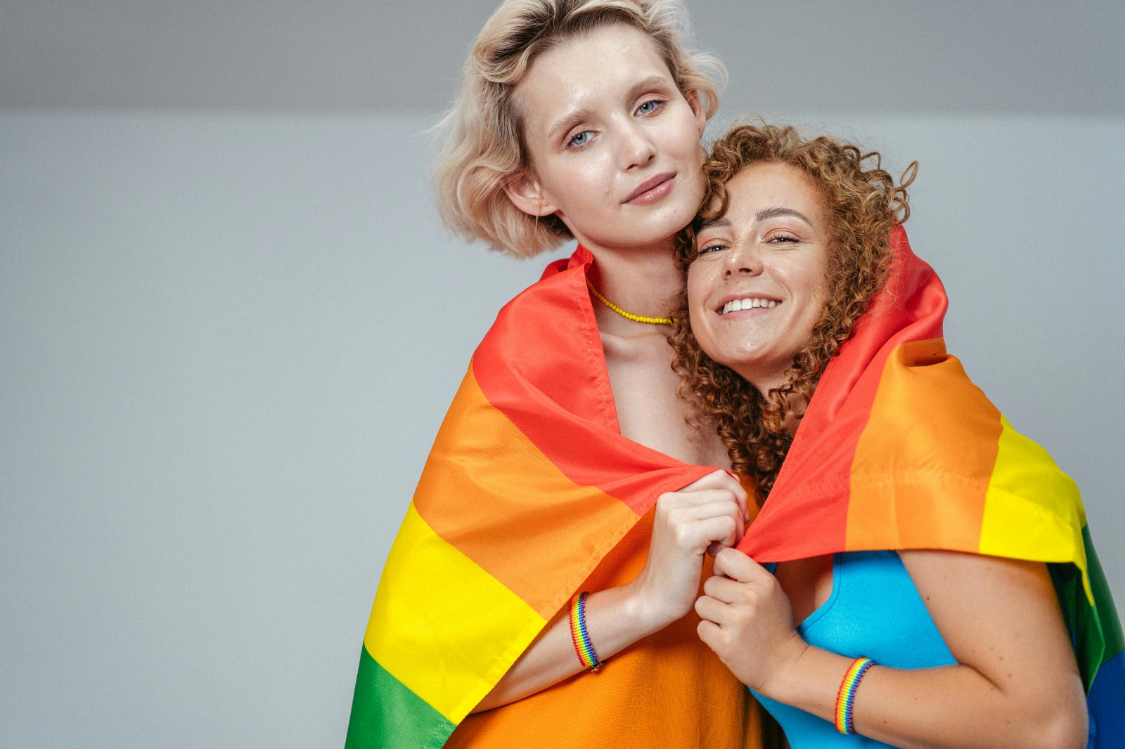 Two women wrapped together in a rainbow pride flag